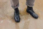 Black Samelin M77 Norwegian combat boots in full-grain leather worn on wet sand, demonstrating water-resistant durability and rugged grip