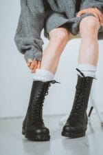 Black high aviator leather boots worn with white socks, lace-up military-style design with rugged sole for everyday and outdoor wear
