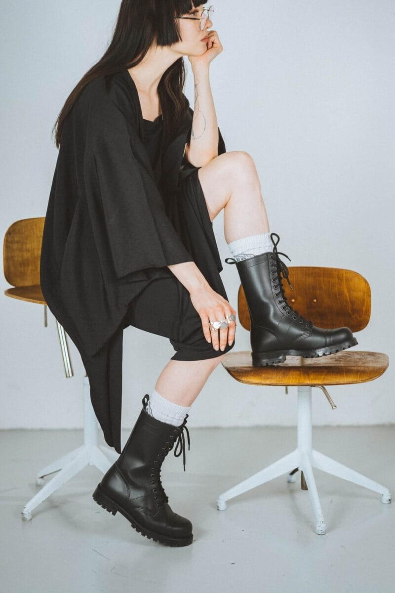 Black high aviator leather boots worn with casual outfit, lace-up military-style boots with rugged sole for everyday fashion and outdoor wear