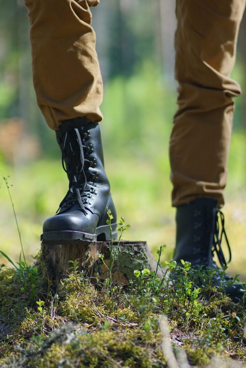 Black Samelin M77 Norwegian combat boots in full-grain leather worn outdoors on forest terrain, showcasing rugged grip and durability